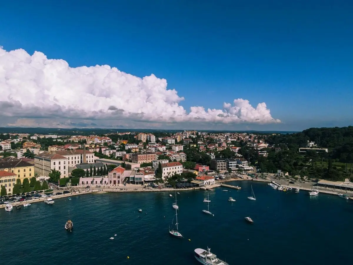 A vibrant aerial view of Rovinj, Croatia, showcasing its stunning coastline, colorful buildings, and boats on the Adriatic Sea.