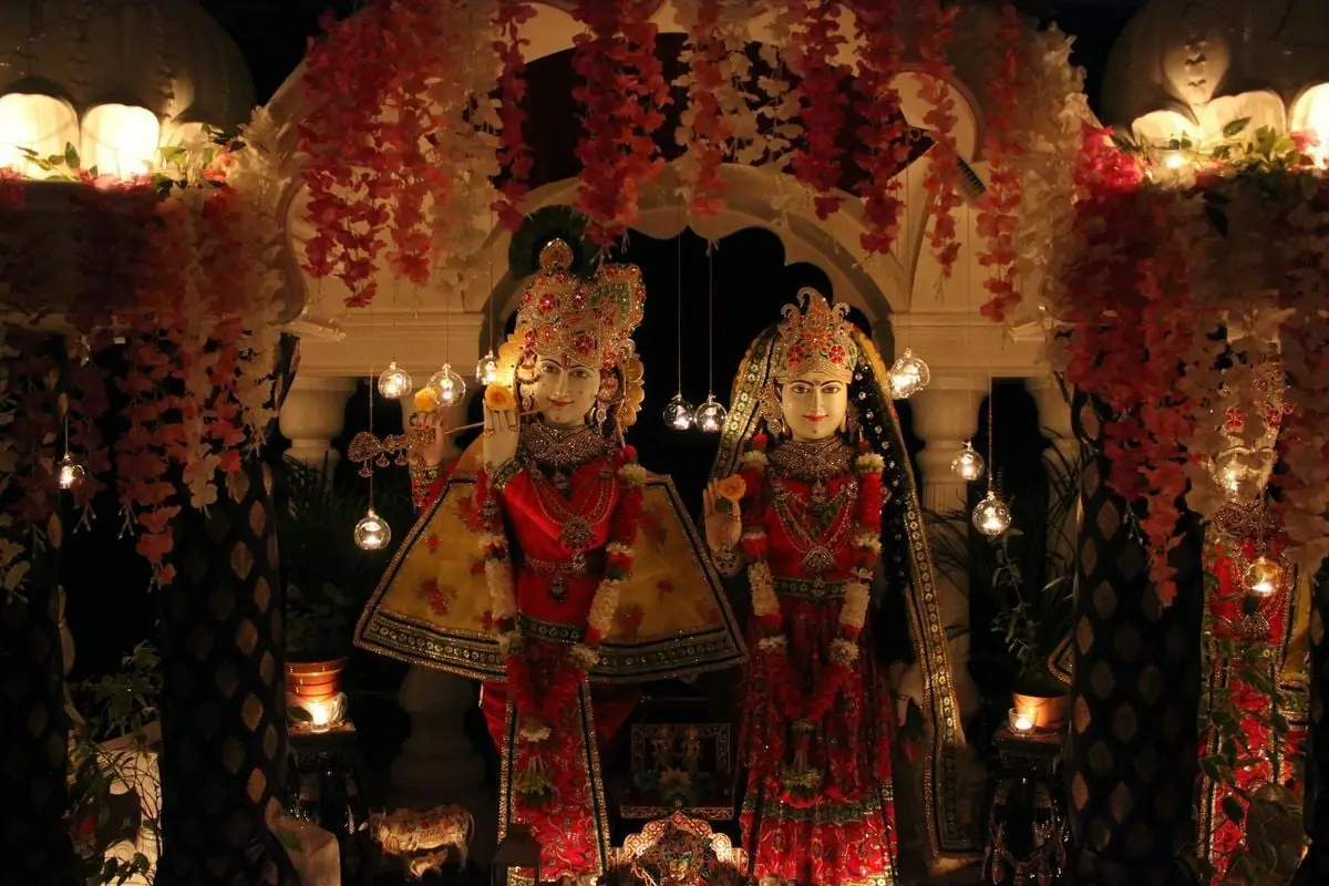 Vibrant display of Hindu deities adorned with flowers and lights during a festival celebration.