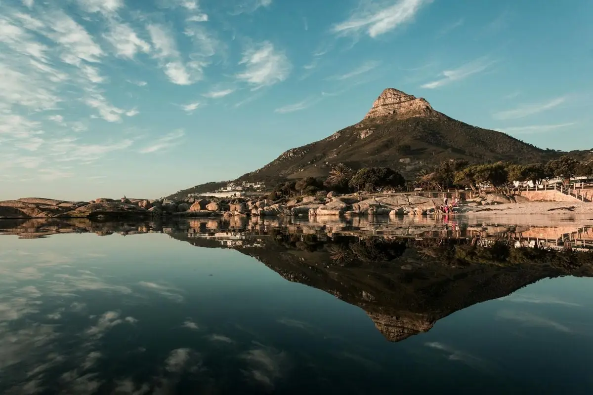 Stunning reflection of Lion's Head mountain in tranquil Cape Town waters at dawn.