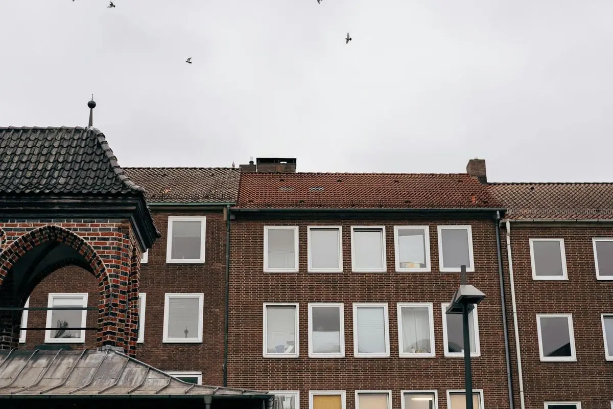 Charming brick buildings in Lübeck, SH, Germany, with birds flying overhead.