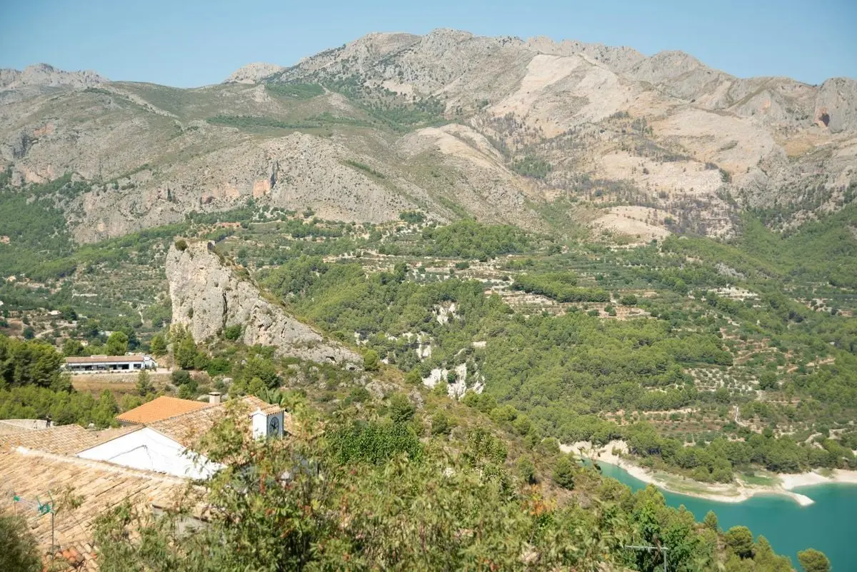 Stunning aerial view of Guadalest, showcasing mountains and greenery under clear skies.
