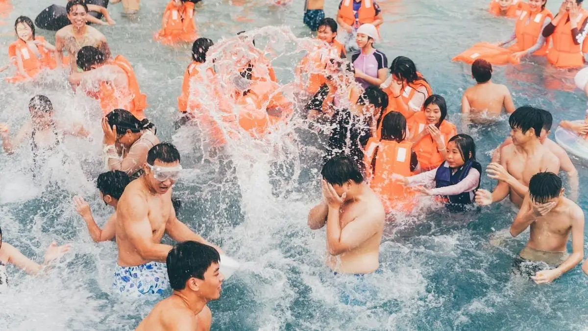 A lively group of people enjoying a summer pool party with splashes and joy, engaging in water fun and laughter.