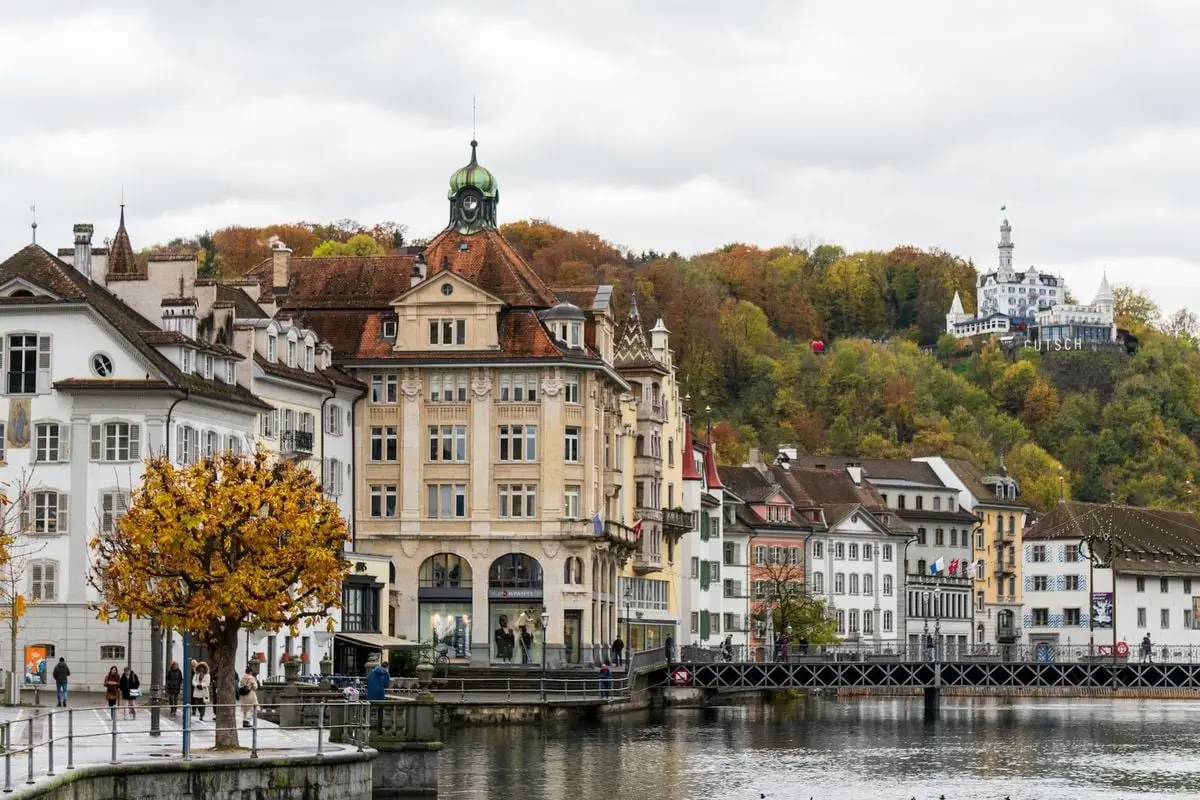 Charming view of Lucerne's waterfront with autumn foliage and historic architecture.