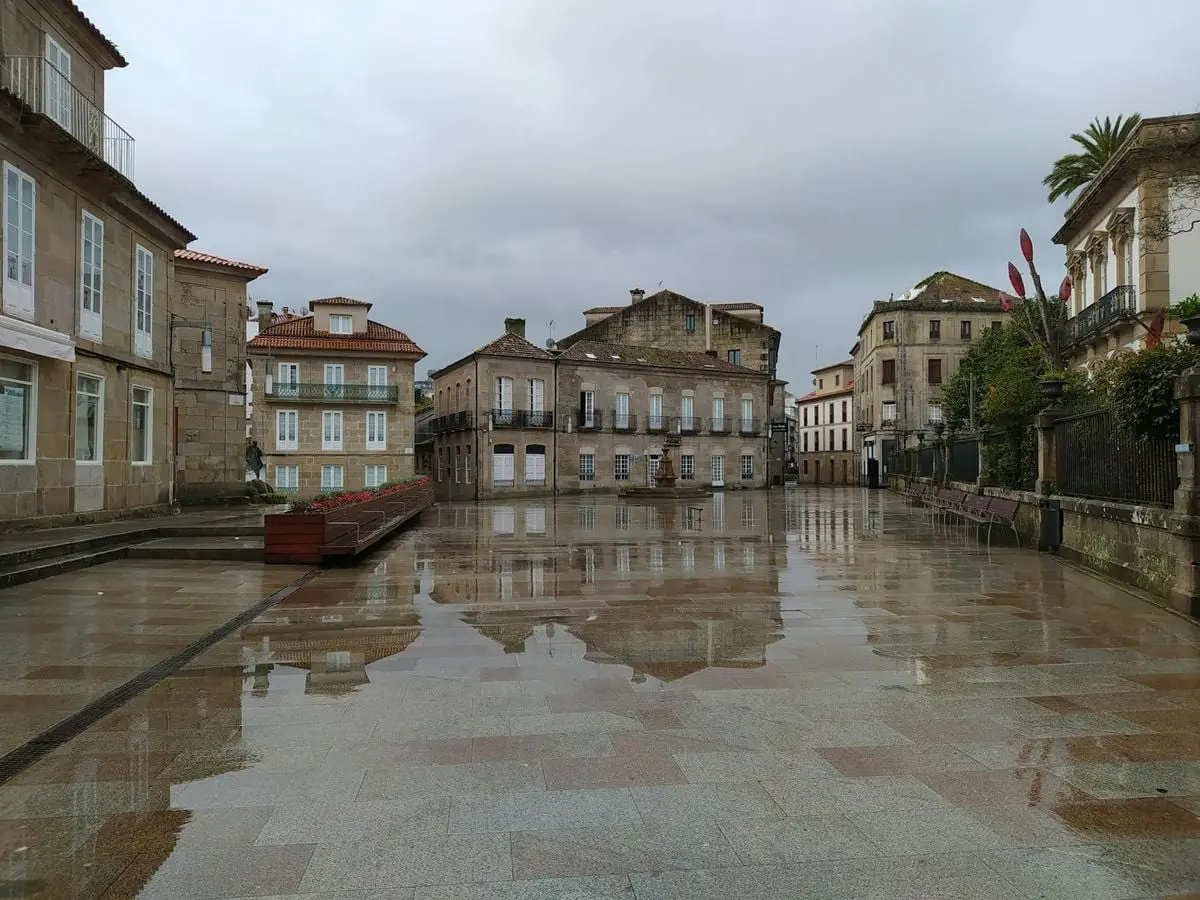 Wet square reflecting vintage buildings on a rainy day. Empty urban scene with historic charm.
