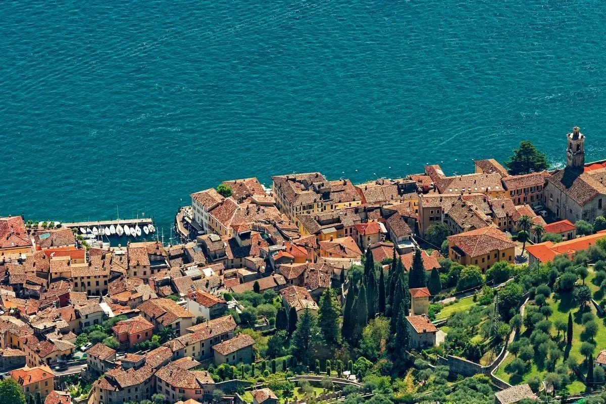 Stunning aerial view of an Italian lakeside town with terracotta roofs by a blue lake.