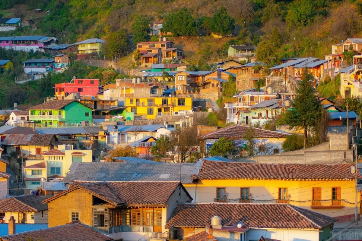 A vibrant hillside town with colorful houses under warm daylight, showcasing diverse architecture.