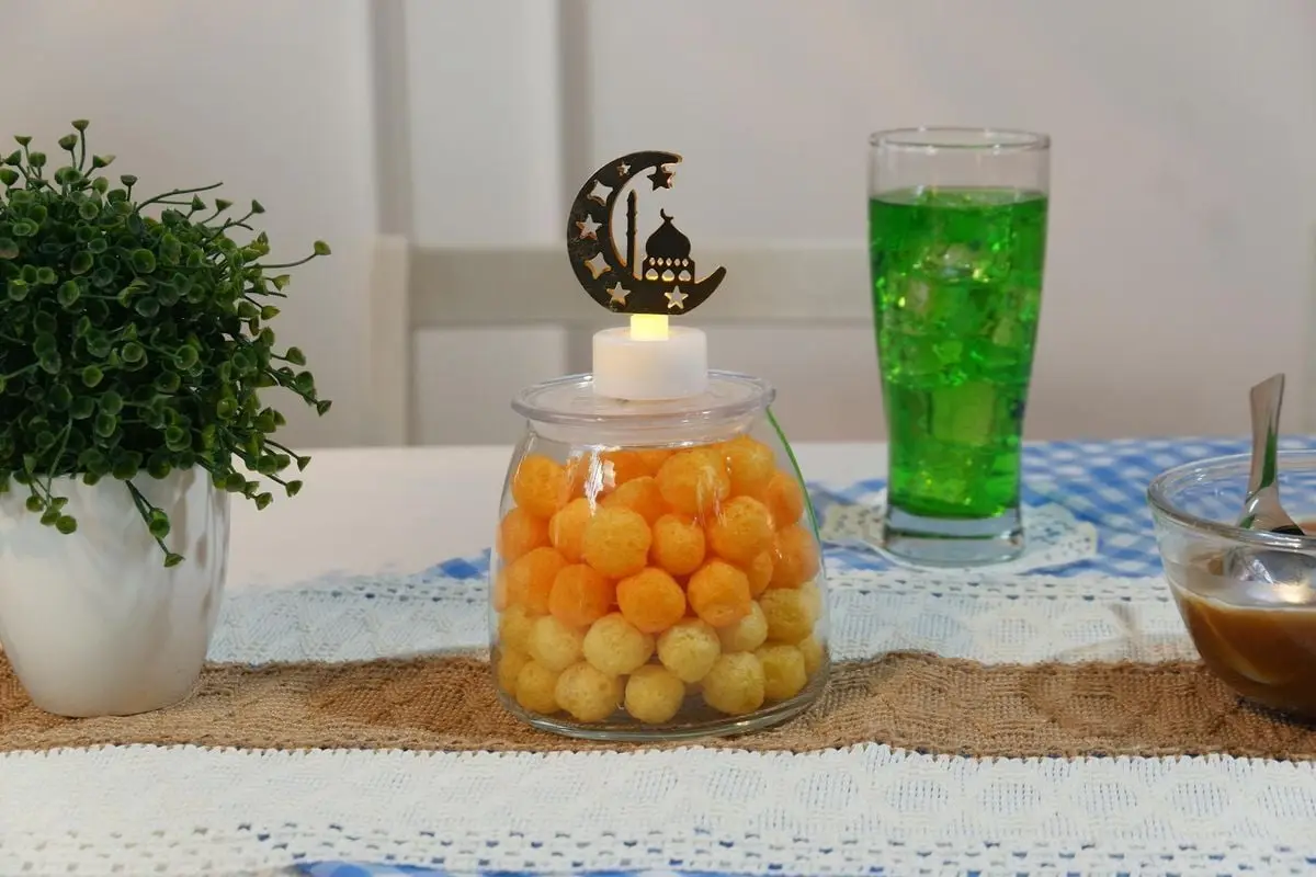 Colorful Ramadan-themed table setting with sweets, green drink, and decorative elements.