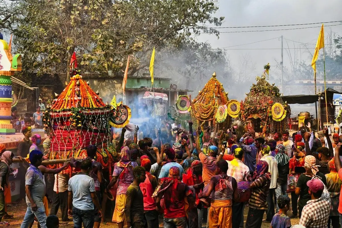 Colorful Holi festival celebration with crowd and decorations in Odisha, India.