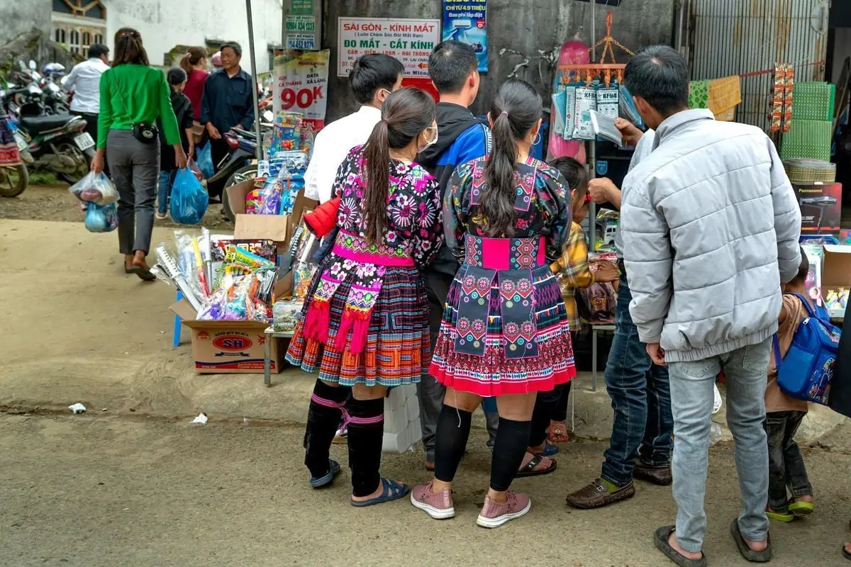 People in vibrant traditional attire shopping at a busy outdoor market.