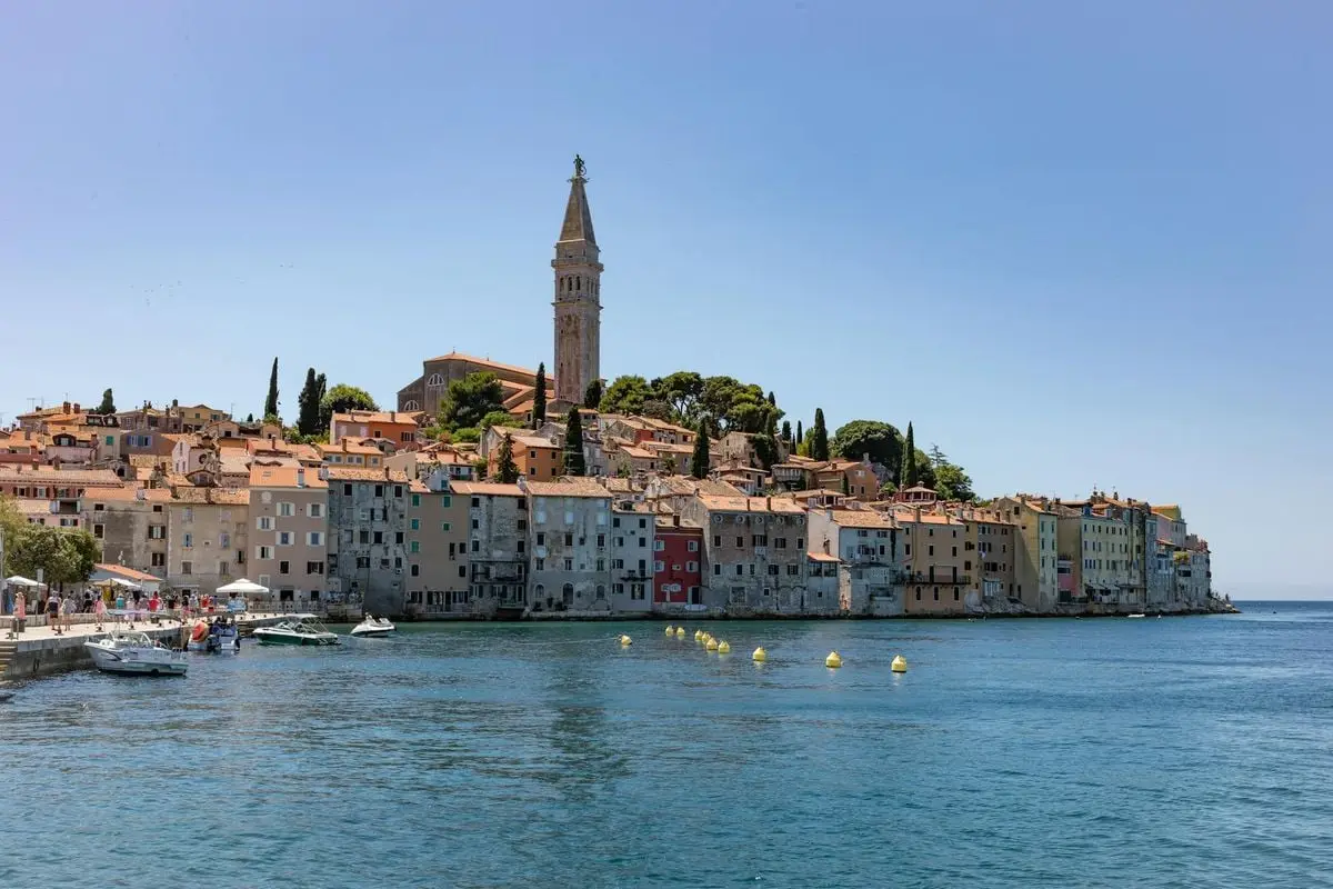 Beautiful view of Rovinj's colorful waterfront and church tower under a clear blue sky.