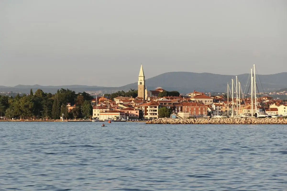 A picturesque view of Izola, Slovenia, featuring its harbor, church tower, and surrounding buildings.