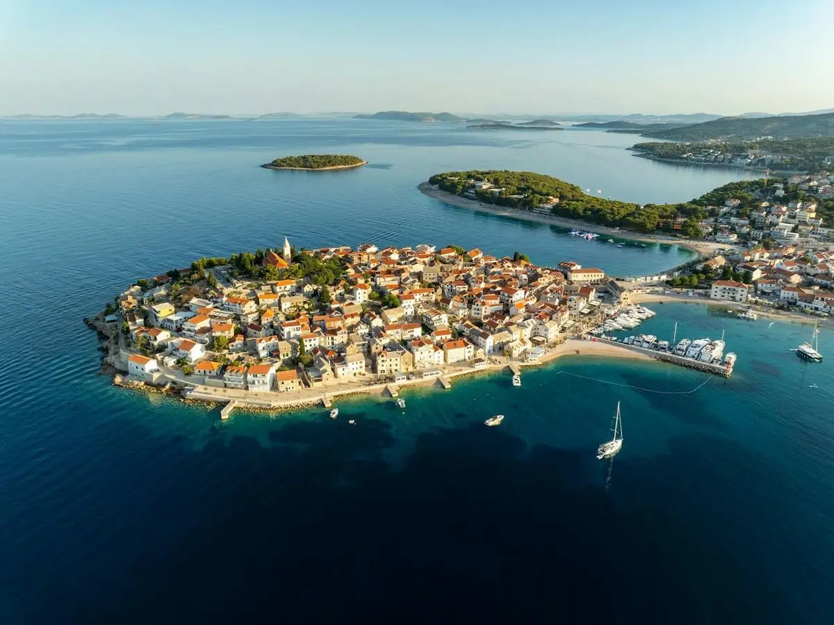 Stunning aerial view of the island town of Primošten, Croatia, surrounded by clear blue sea.