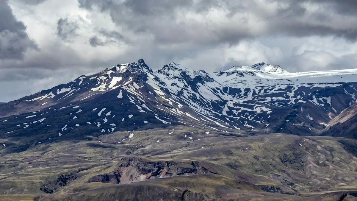 A breathtaking view of Iceland's snow-covered mountains under a dramatic sky.
