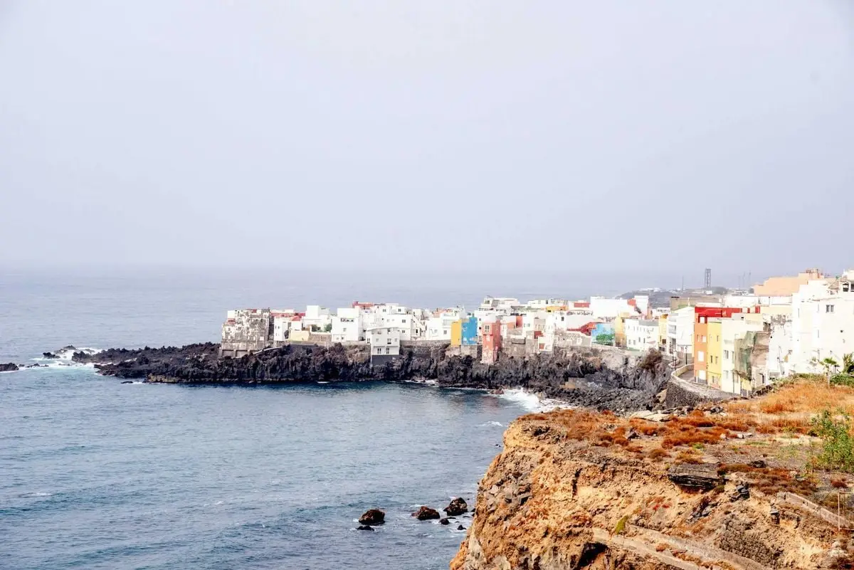 Vibrant coastal view of Puerto de la Cruz, Spain, showcasing colorful buildings on the rocky shore.
