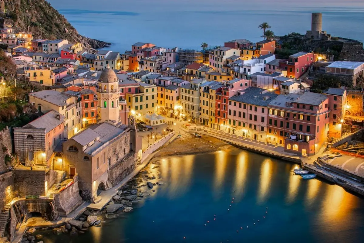 Stunning aerial view of Vernazza's colorful buildings and serene coastline during evening twilight.