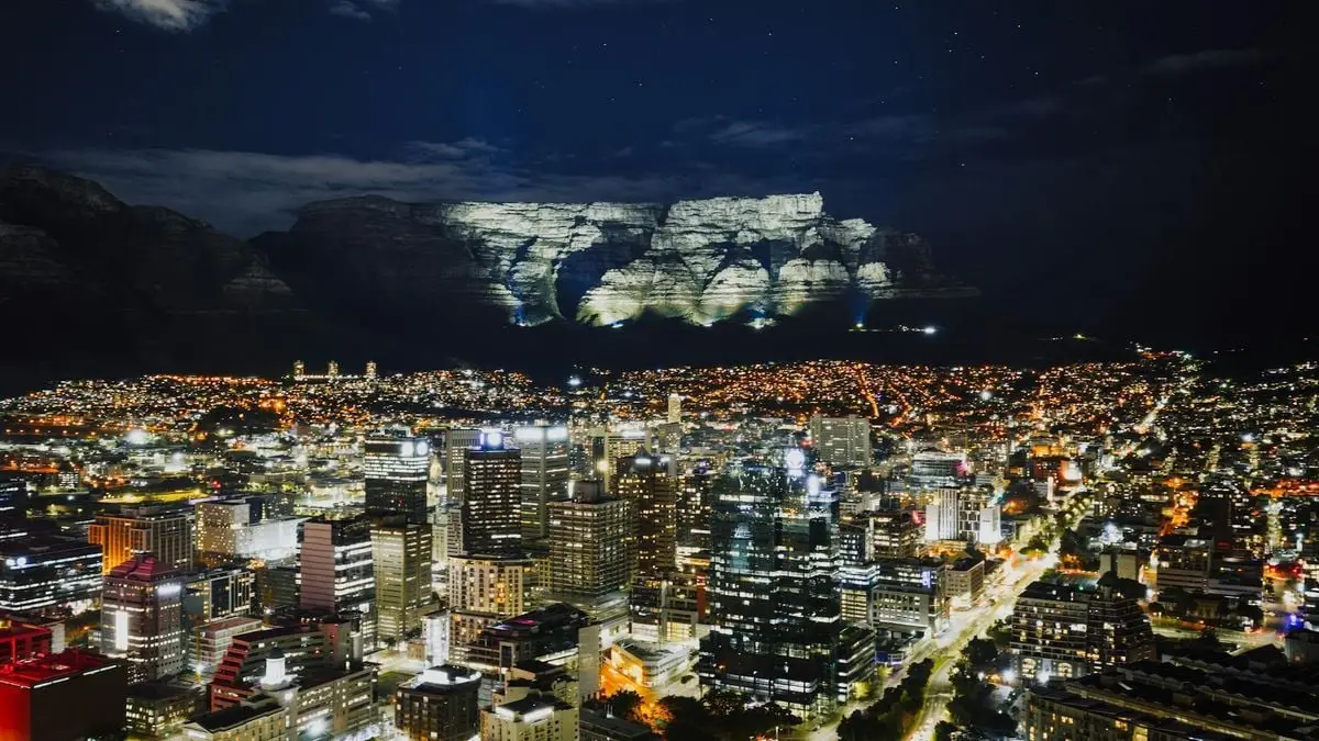 Stunning aerial view of Cape Town's illuminated cityscape with Table Mountain in the background at night.
