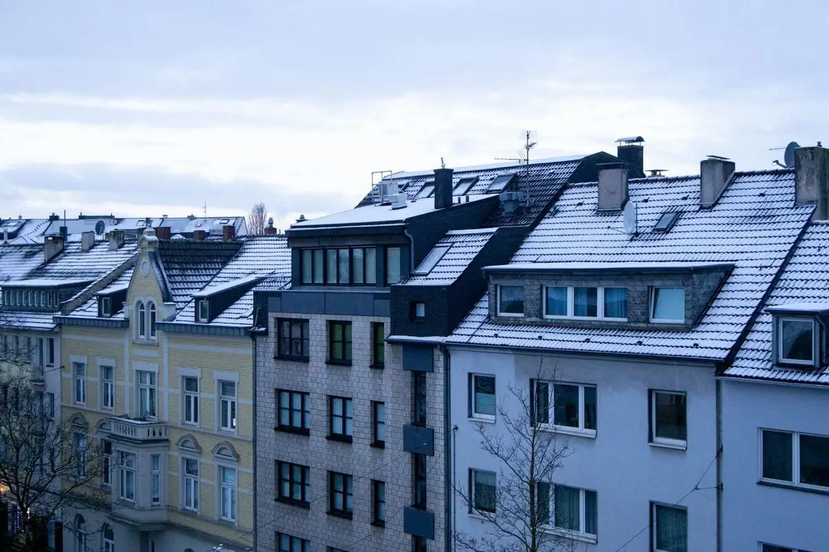 Winter view of snow-covered roofs on European cityscape at dusk.