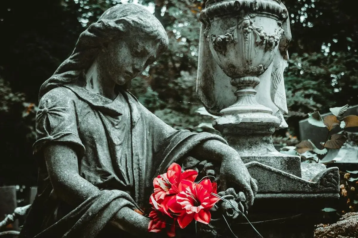 A solemn stone statue holding a vibrant red bouquet, symbolizing eternal beauty and remembrance.