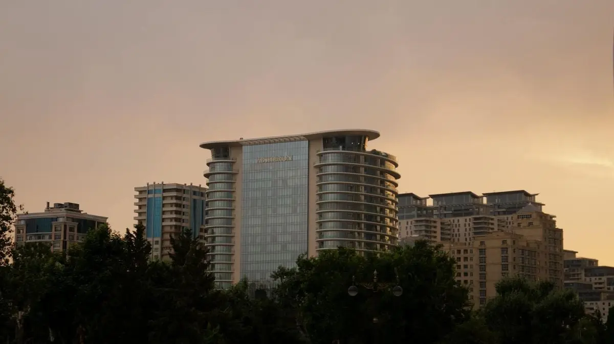 Capture of Baku's urban skyline at dusk featuring modern architecture and a luxury hotel.