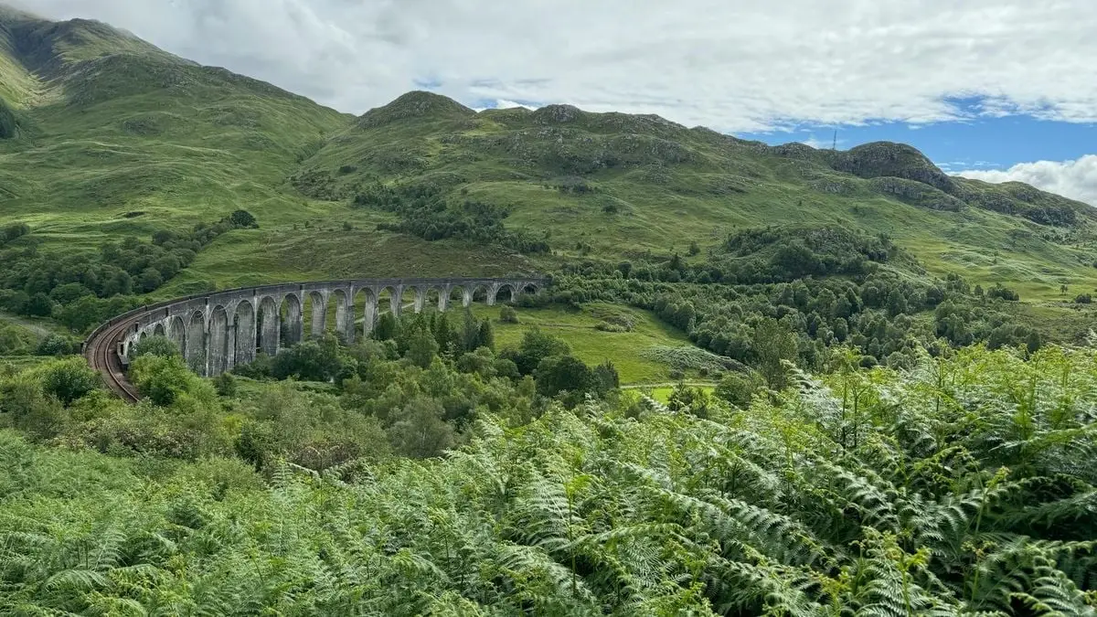 Captivating view of the iconic Glenfinnan Viaduct amid lush greenery in Scotland.