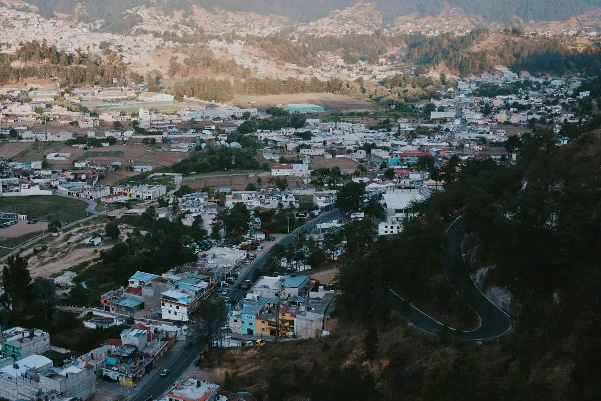 Aerial view of a picturesque mountain town nestled in lush greenery and rugged terrain.