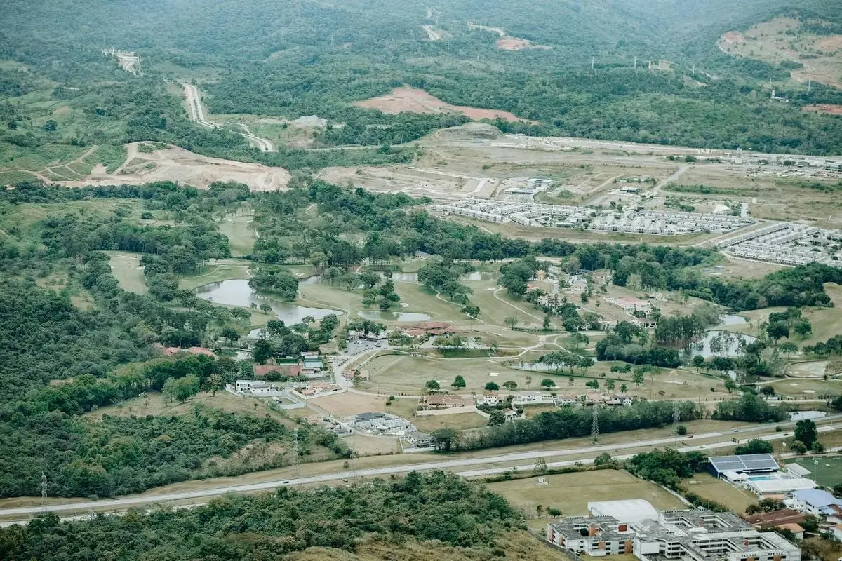 Aerial view of a lush countryside with forests, fields, and a small settlement.