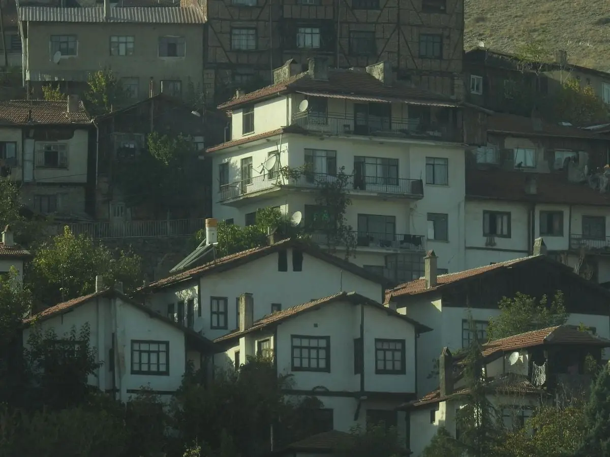 Scenic view of residential houses with traditional architecture in a hillside town, bathed in warm light.