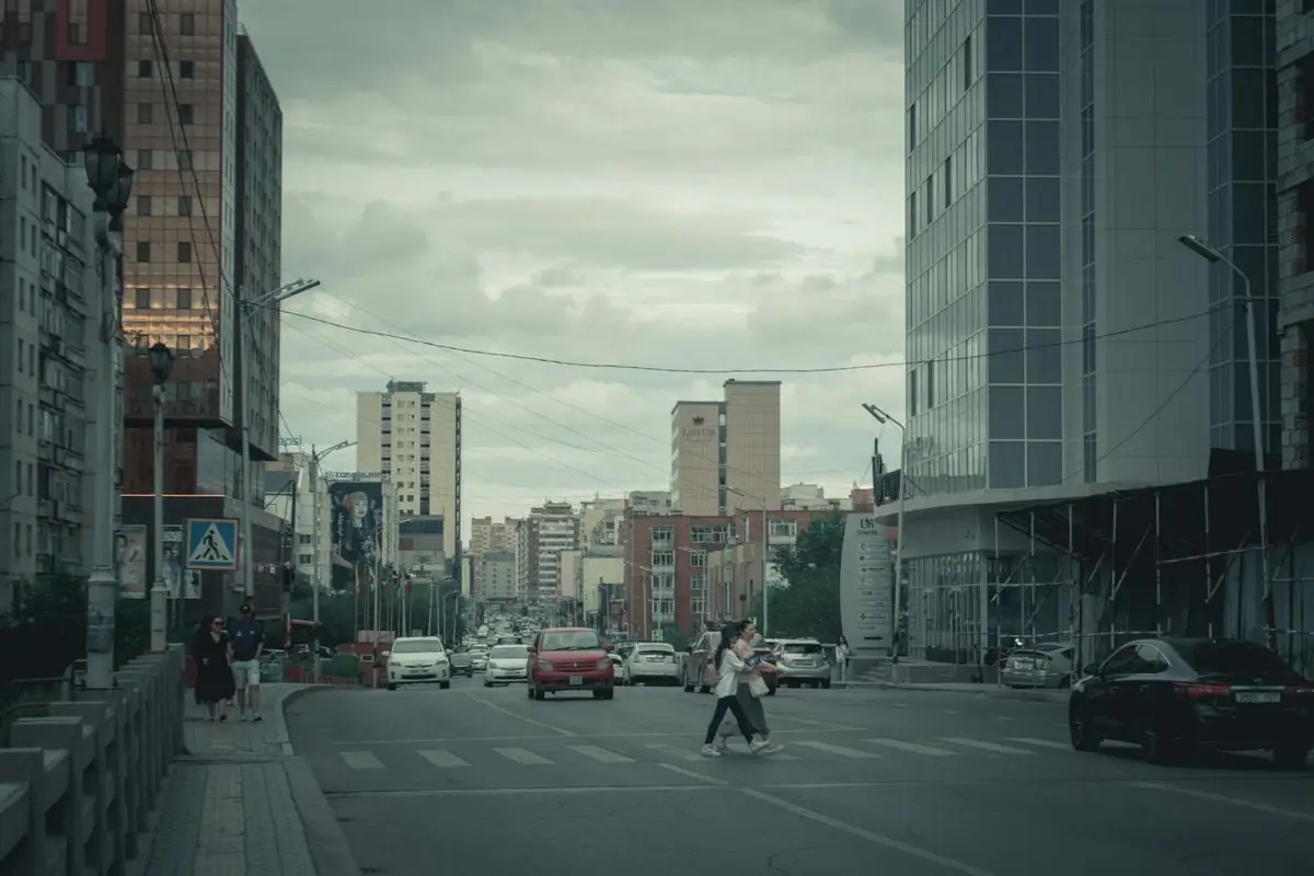 A lively day in the city with pedestrians crossing streets surrounded by modern architecture.