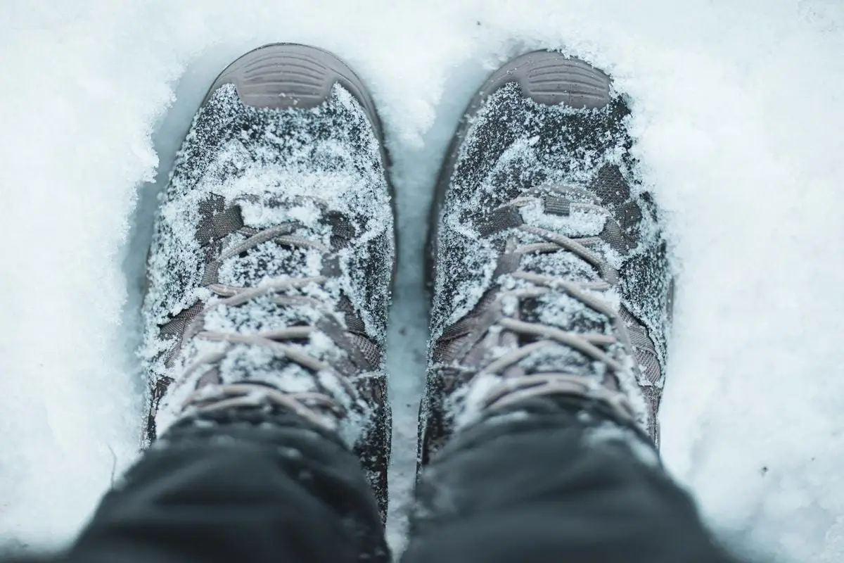 Close-up of snow-covered hiking shoes in a winter scene, capturing the essence of outdoor adventures.