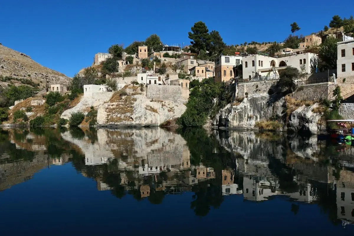Ancient stone houses reflected in calm waters of Halfeti, a scenic town in Türkiye.