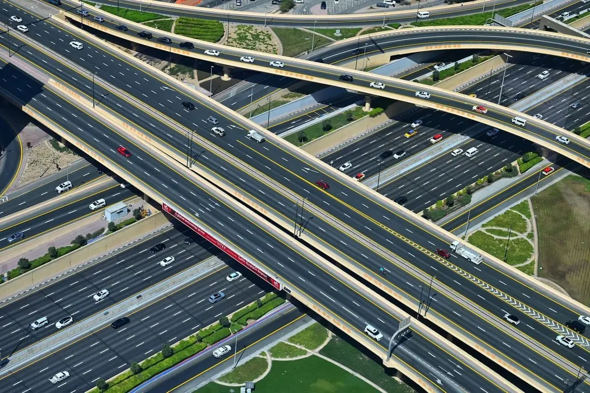 Aerial shot of a modern highway interchange with various vehicles and overpasses.