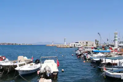 Beautiful coastal scene of Foça harbor in İzmir, Türkiye with fishing boats and clear blue skies.