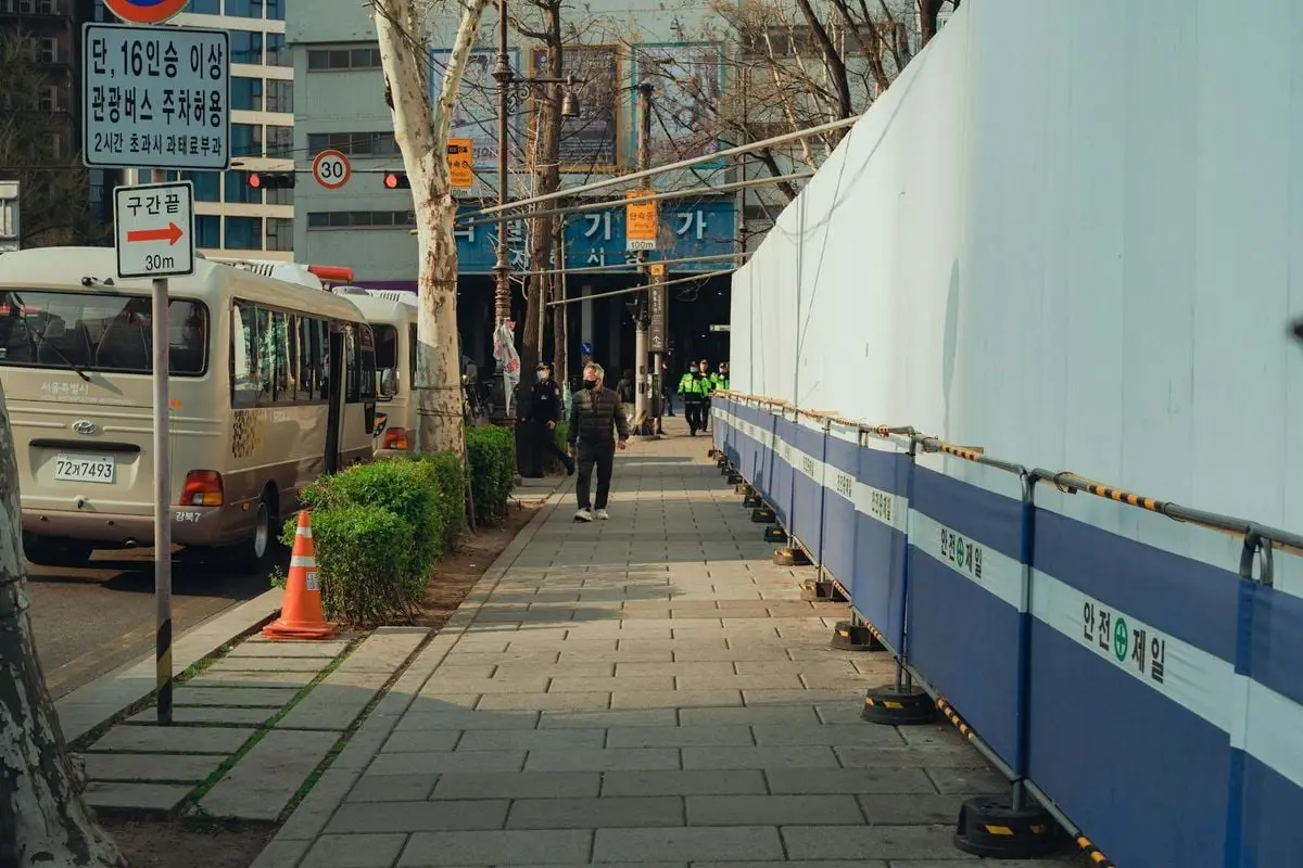A street in Seoul, South Korea showing buses, pedestrians, and a construction site.