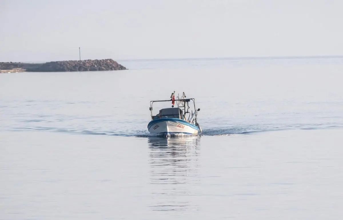 Small fishing boat on serene waters in Foça, Türkiye, during winter.