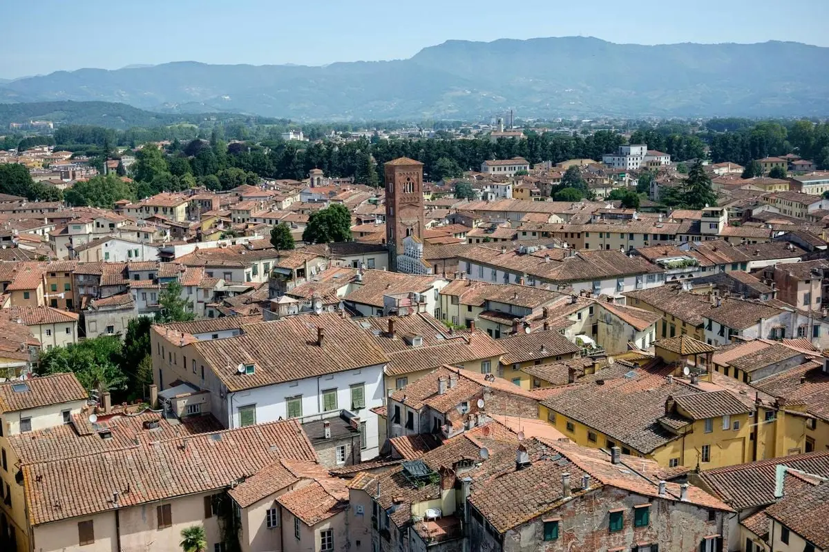 A stunning aerial view of Lucca, Italy featuring historic rooftops and distant mountains.