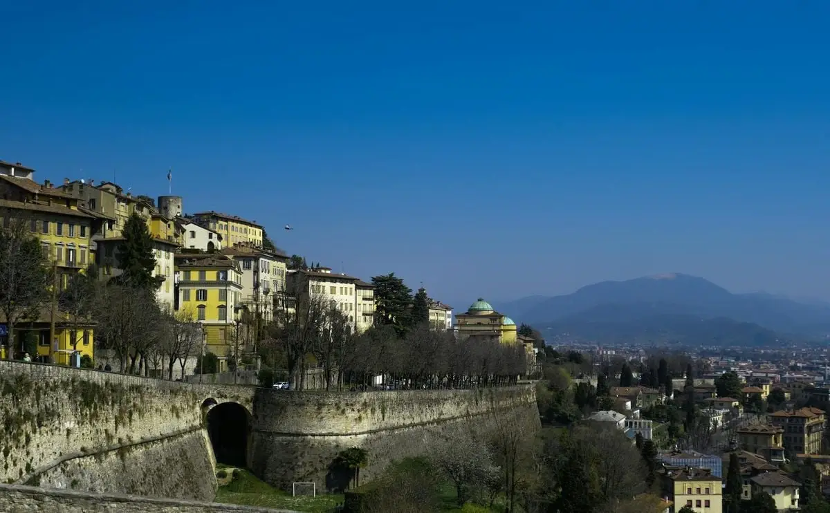 Picturesque view of Bergamo's historic old town with rooftops and a beautiful skyline against clear blue skies.