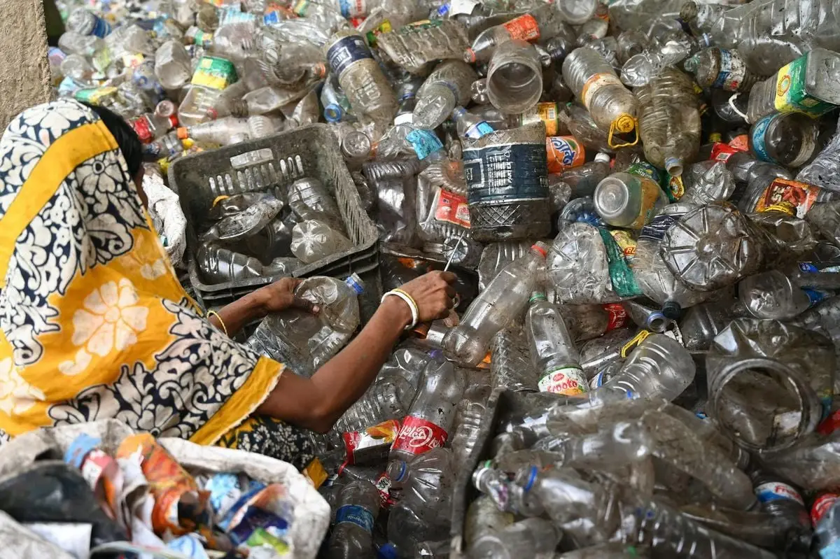 A woman sorting plastic bottles at a recycling center, highlighting environmental conservation.