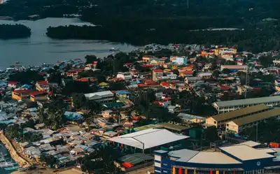A vibrant aerial view of a coastal town with diverse colorful rooftops and lush greenery.
