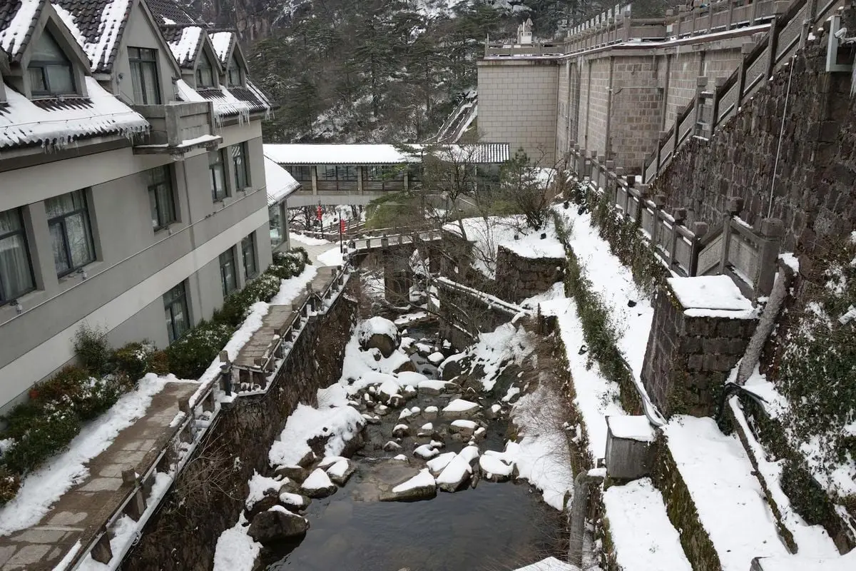 Snow-covered resort area with a stone path and creek during wintertime.