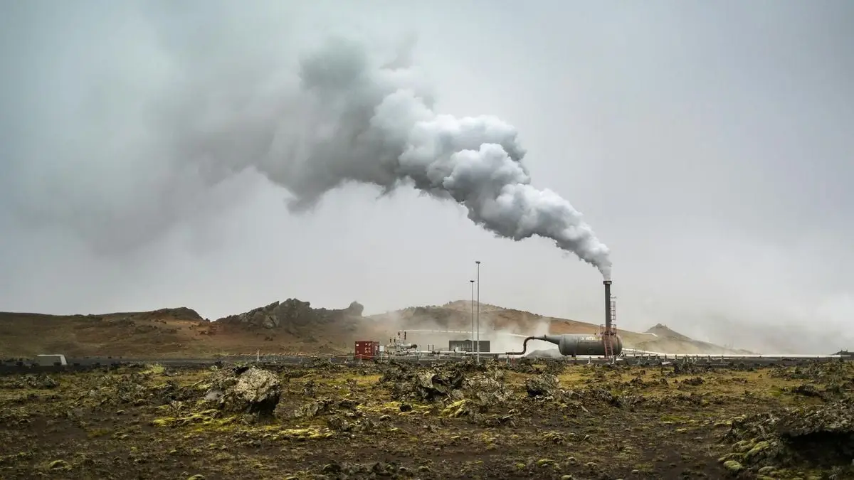 A large chimney releases smoke in the rural countryside, illustrating industrial activity.