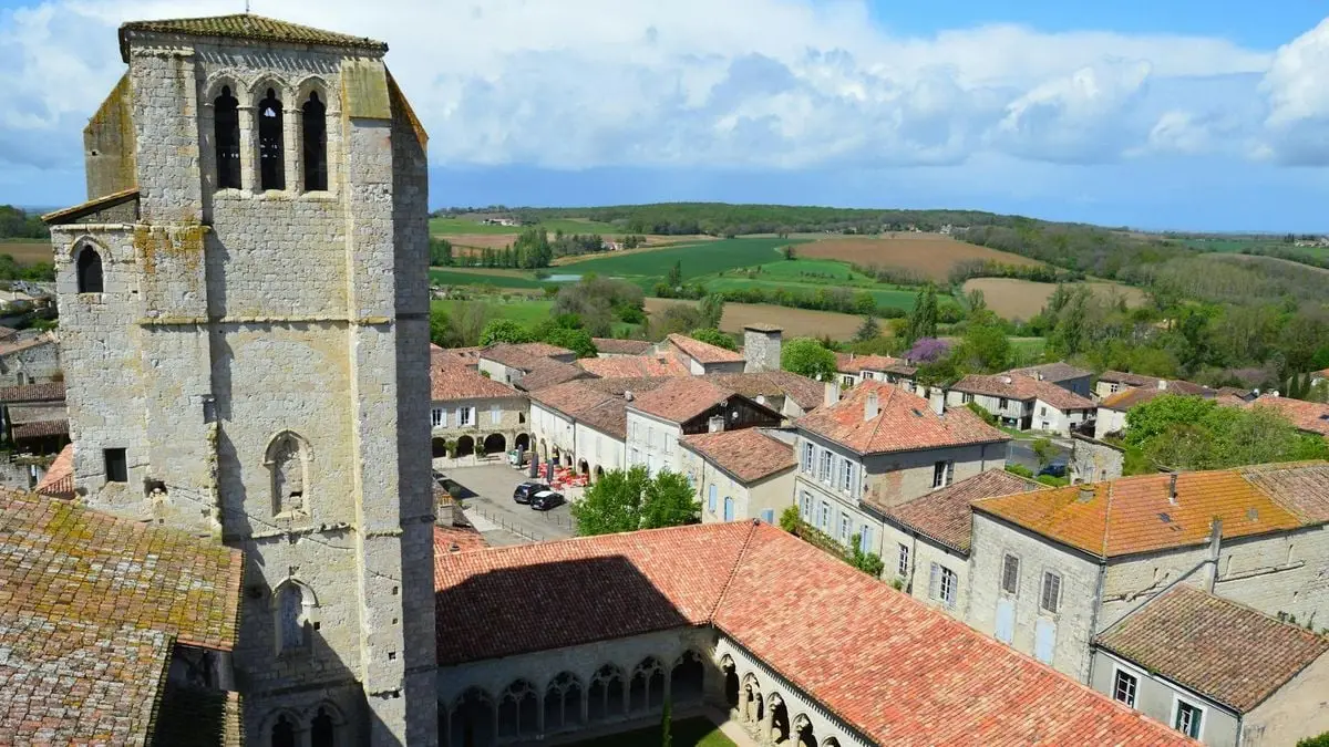 Drone view of La Romieu, France, showcasing historic architecture and countryside.