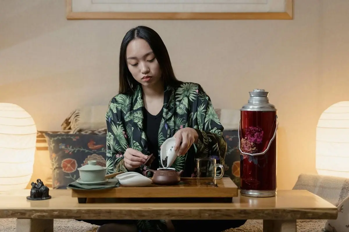 Woman performing a traditional tea ceremony indoors, creating a calm atmosphere.