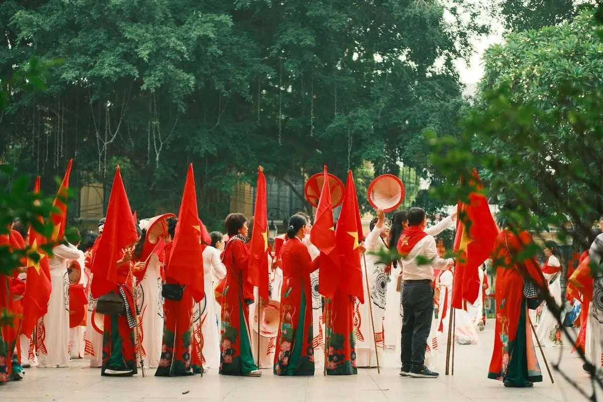 Traditional Vietnamese parade with participants holding red flags, celebrating culture outdoors.
