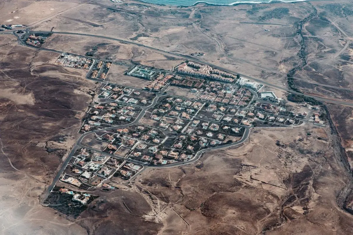 Aerial view of a coastal residential area surrounded by arid landscape.