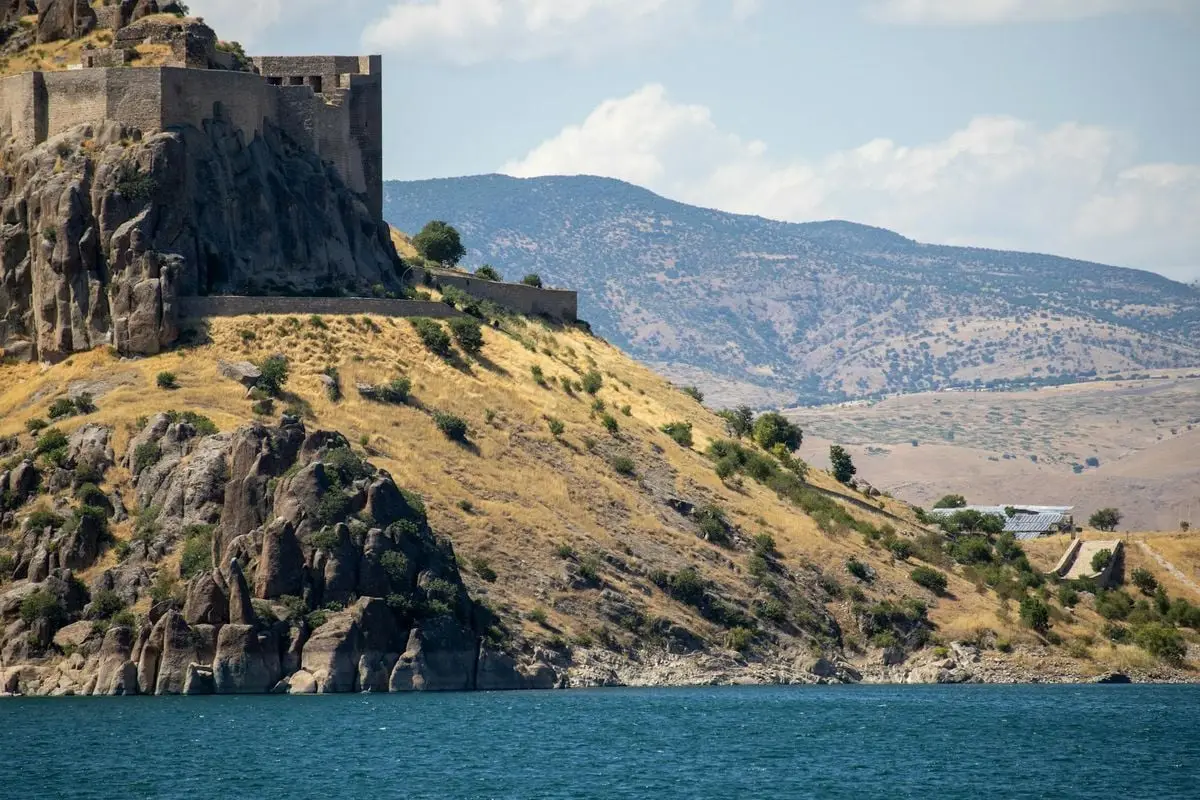Scenic view of Pertek Castle standing majestically over Keban Lake, showcasing historical architecture amidst stunning natural landscapes.