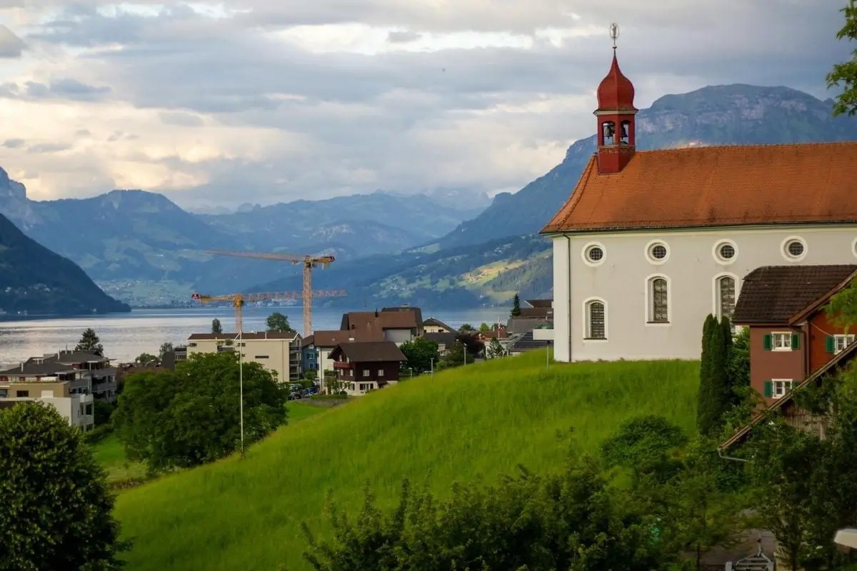 Stunning view of a church overlooking Lake Lucerne and mountains, capturing Switzerland's serene beauty.