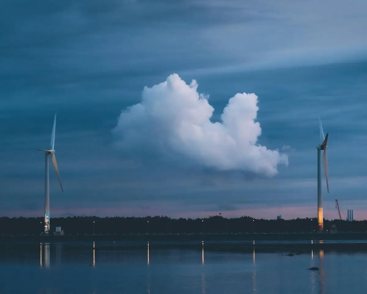 Wind turbines on calm water at twilight in Taichung, reflecting the sky's serenity.