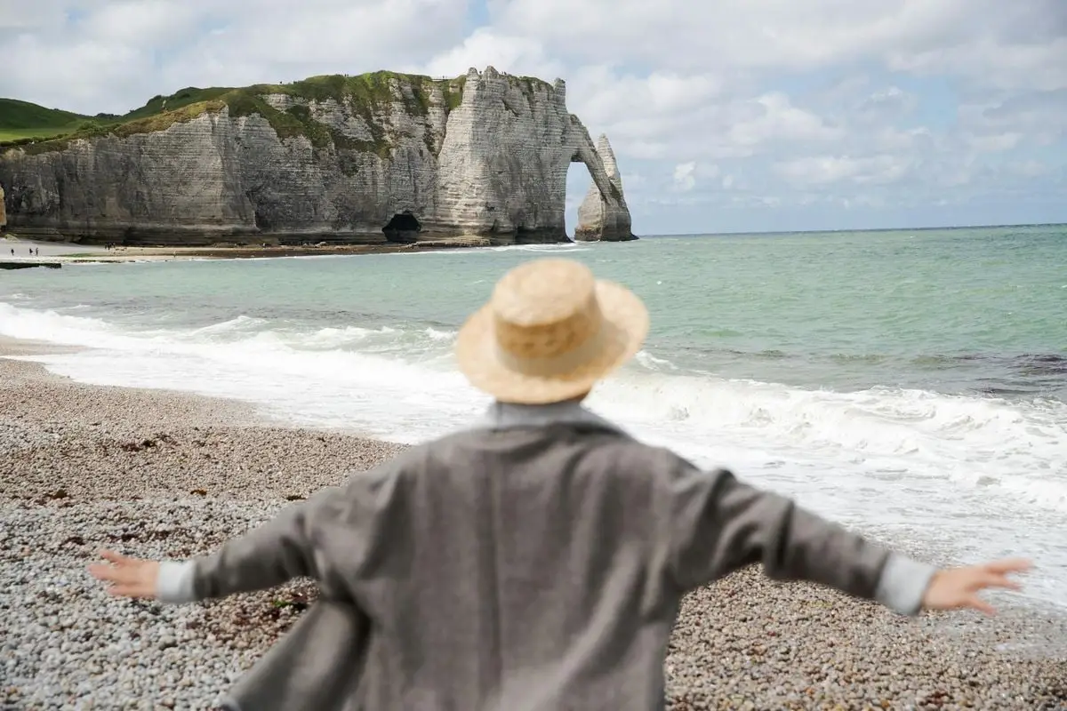 Faceless woman admiring the iconic cliffs at Étretat, Normandy, France.