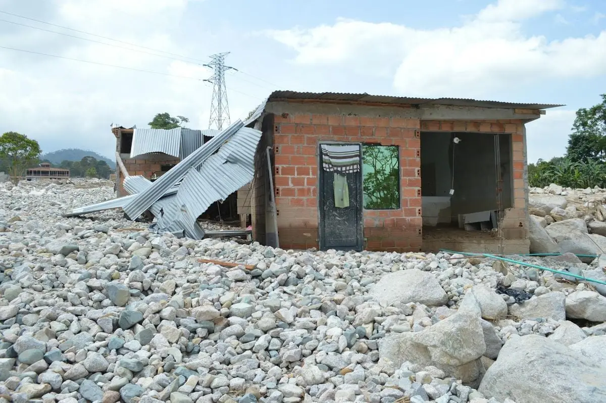 A damaged house surrounded by rocks in Mocoa, Colombia, highlighting natural disaster impact.
