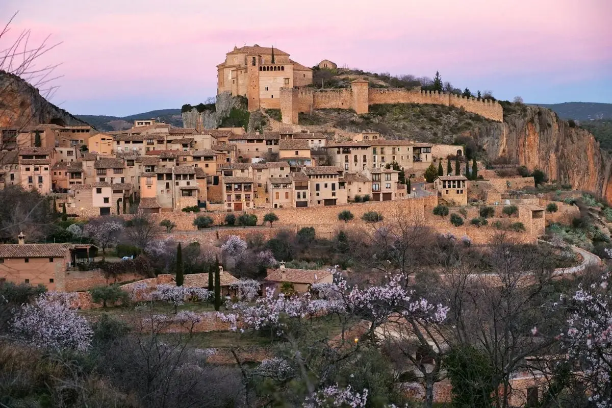 Charming sunset view of Alquézar with its historic hilltop fortification and blooming cherry trees.